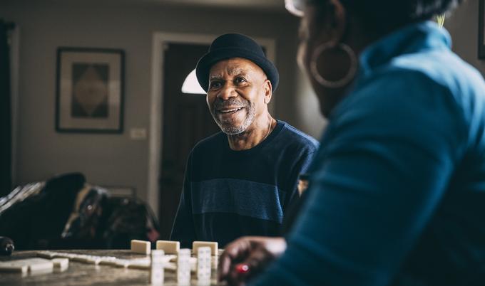Man smiling and playing dominoes