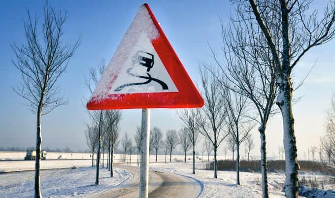 Car driving on winding road in the snow.