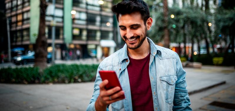 Man smiling using mobile phone at the street