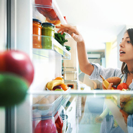 Woman grabbing vegetables out of the fridge.