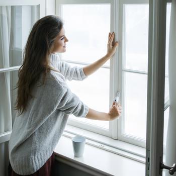 Woman with hand on window handle.