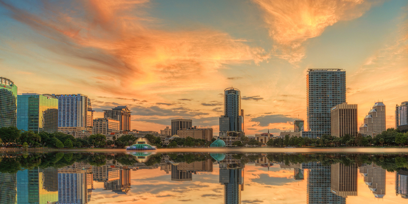 A colorful sunset over Lake Eola and Orlando, Florida with reflections captured off the lake.