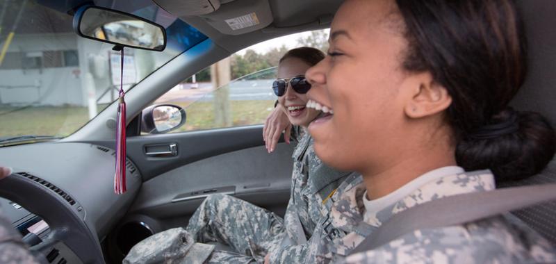women in military uniforms driving and laughing