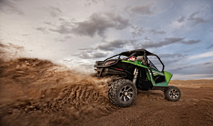 A person driving an ATV kicking up dirt behind it.