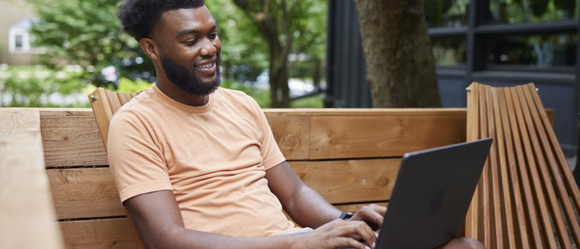 Photo of a young African American man, working from a remote location on his computer