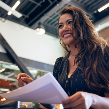 A smiling woman holding paperwork.
