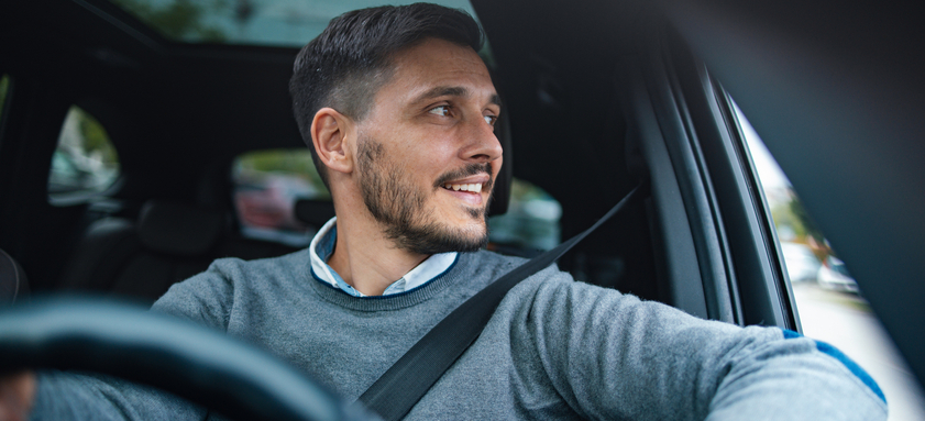 A Happy Handsome Businessman Looking Away While Driving His Car