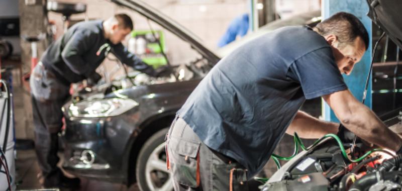 mechanics working under the hood of cars in repair shop