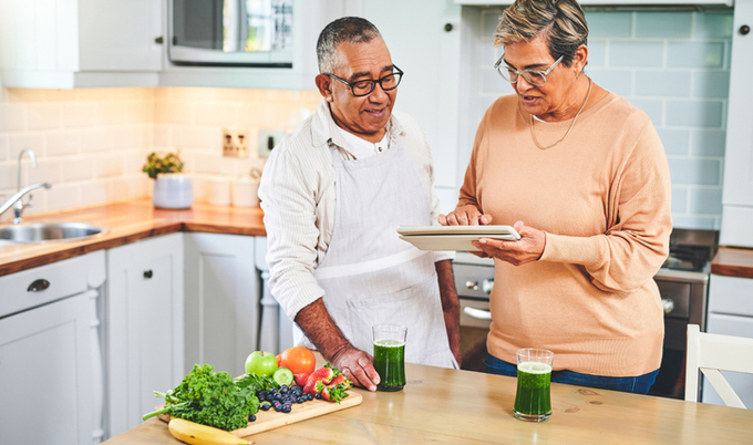 Husband and wife looking at tablet in the kitchen.
