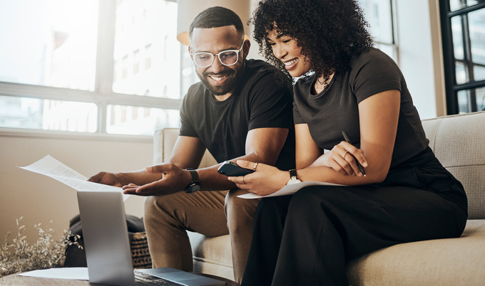 Woman and man sitting in living room sitting in front of laptop