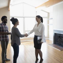 Young couple shaking hands with property manager. 