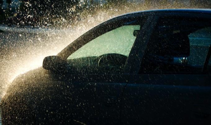 Side view of dark car in heavy rain.
