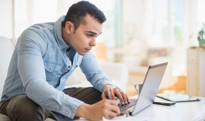 man writing and looking at computer