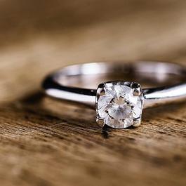 Diamond ring with a silver band on a wooden surface.