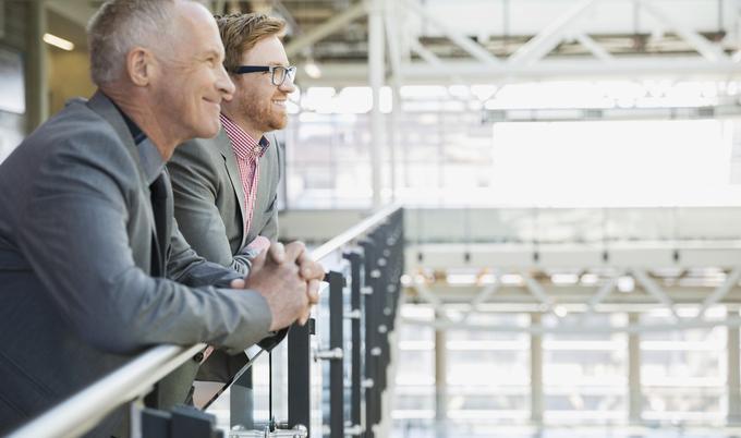Two business men leaning on rail.