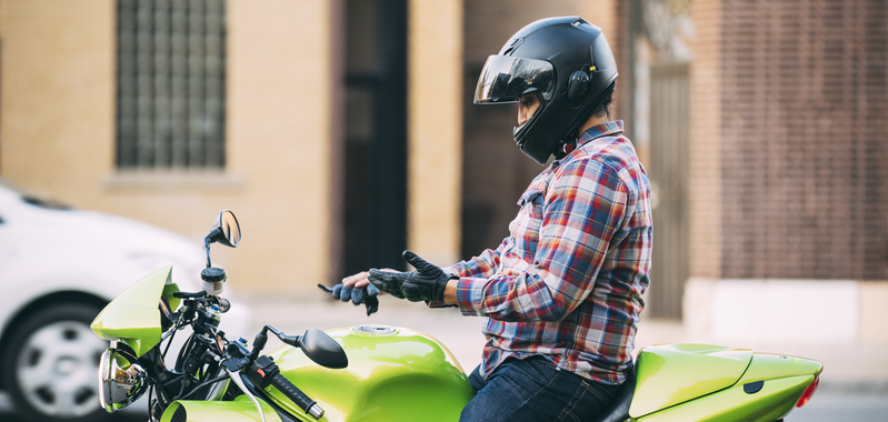 Guy on motorcycle putting gloves on