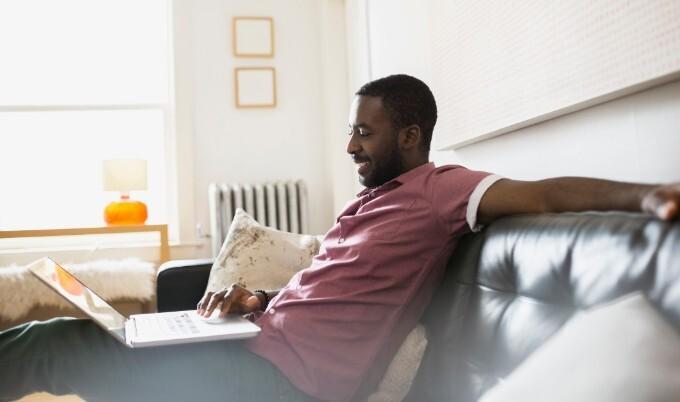 man looking at laptop while sitting on couch. 