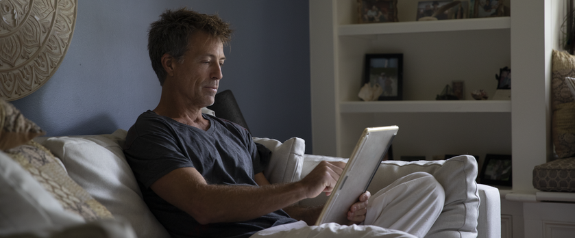 man on tablet lounging at home