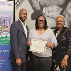 A man and two women at an event standing in front of a New Covenant sign.