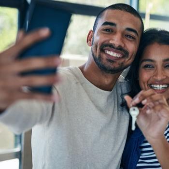 Youngle couple taking a selfie with a key in woman's hand.