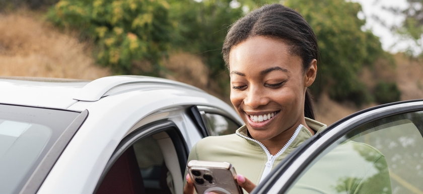 Woman looking at phone outside of car