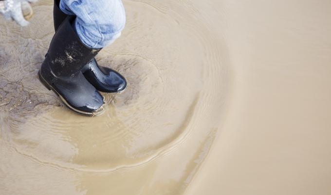 Person in rubber boots walking through a puddle.