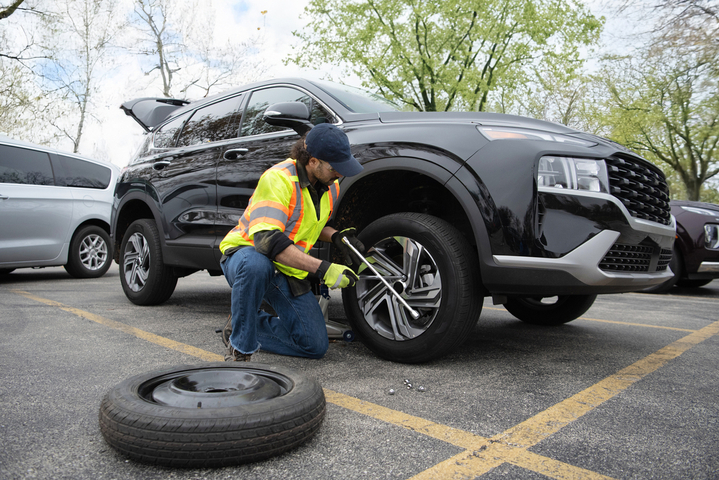 Man with reflective vest changing tire on SUV