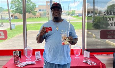 A man stands holding balloons and Circle K gift cards