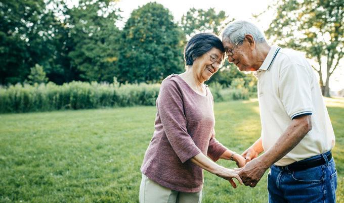 Old couple holding eachothers' hands and putting their heads together.