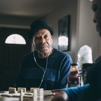 Man listening to music and playing dominoes.