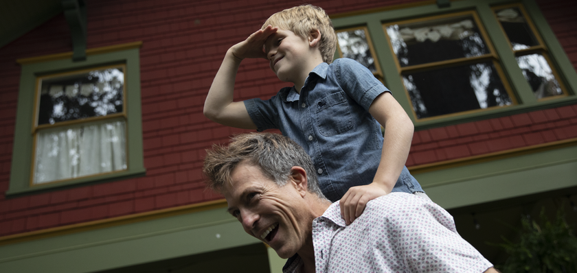 father and son piggy back in front of house