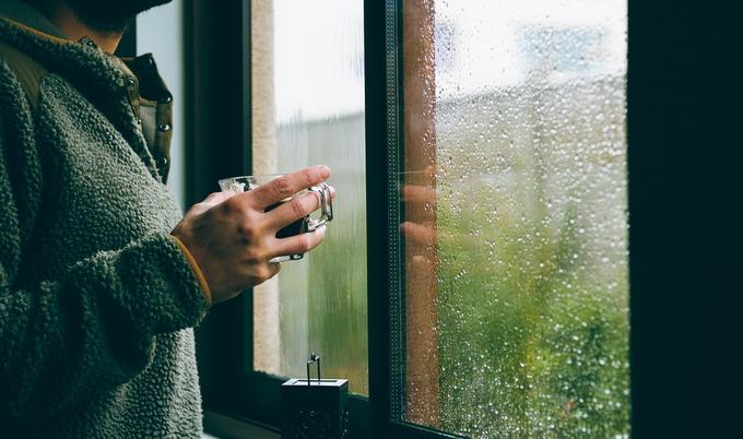 Man looking out a window-on a rainy day.