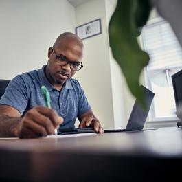 a man sitting at a table using a laptop computer.