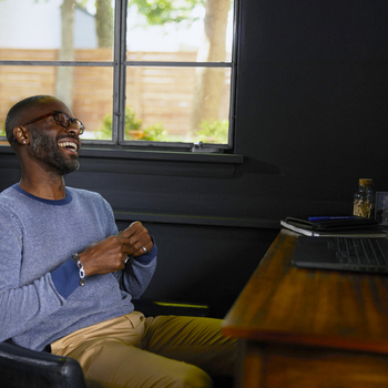 Man laughing while sitting at a desk.