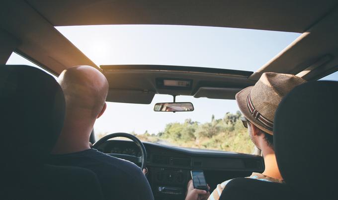 Two friends driving with sunroof.
