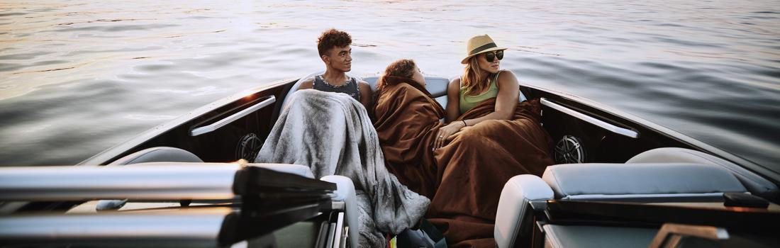 Mother and children riding in bow of boat on summer evening