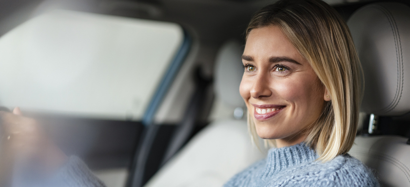 Portrait of smiling young woman driving a car.