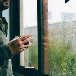 Man looking out a window-on a rainy day.