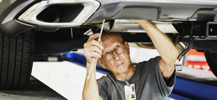 Older man working on car on auto lift in a garage