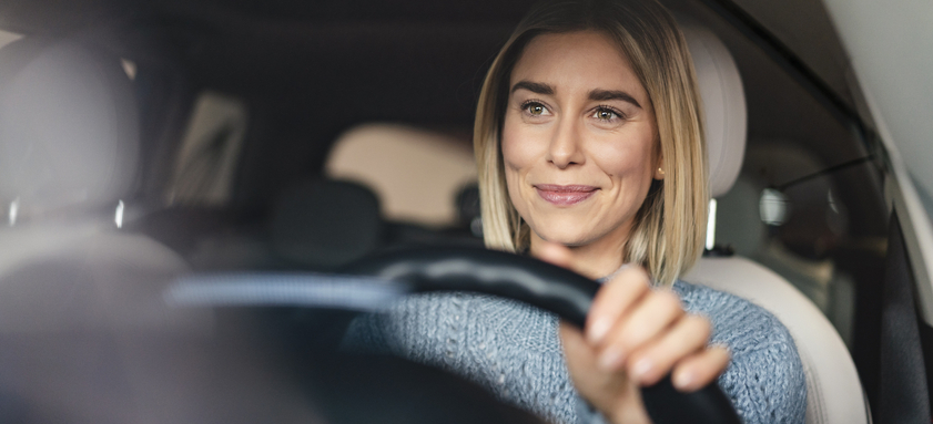 Portrait of smiling young woman driving a car.