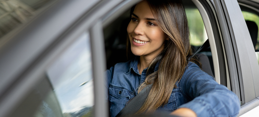 Woman at a showroom going for a test drive in a car.