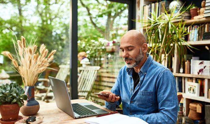Man on phone speaker while sitting at computer