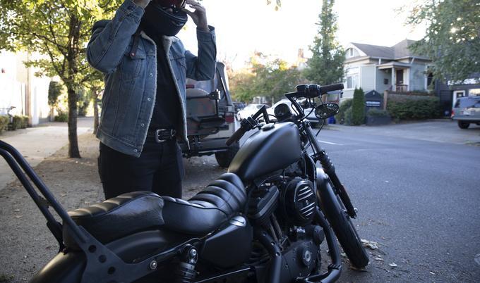 female getting ready to ride motorcycle putting helment on