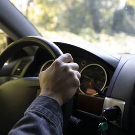 hand on steering wheel inside of a car