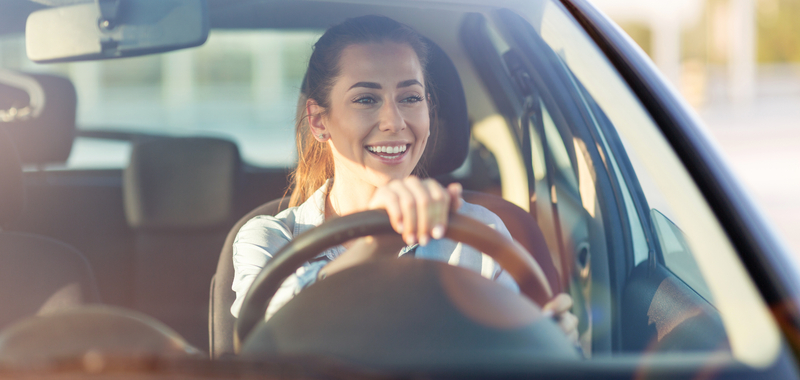 A smiling woman drives her car