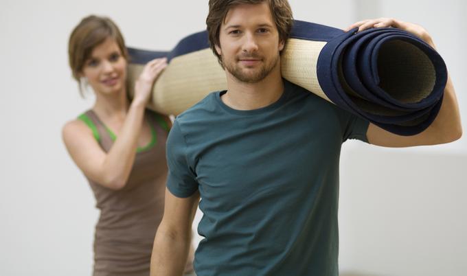 Man and woman carrying rolled-up carpeting.