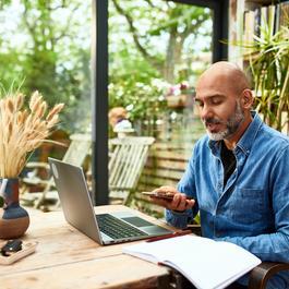 Man on phone speaker while sitting at computer