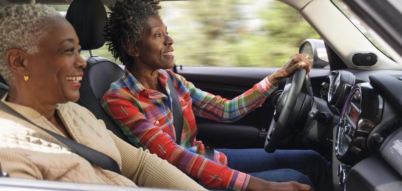 two older women smiling while driving in a car 