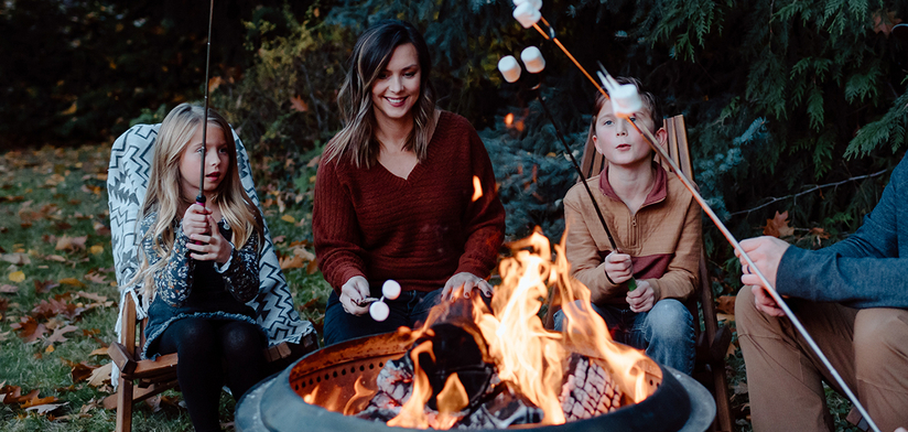 Family roasting marshmallows around fire