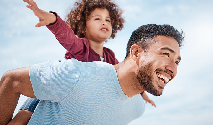 Father giving his daughter a ride on his back as she acted like she was an airplane.